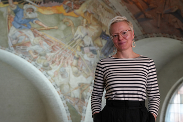 Niina Hämäläinen standing in front of a Kalevala mural